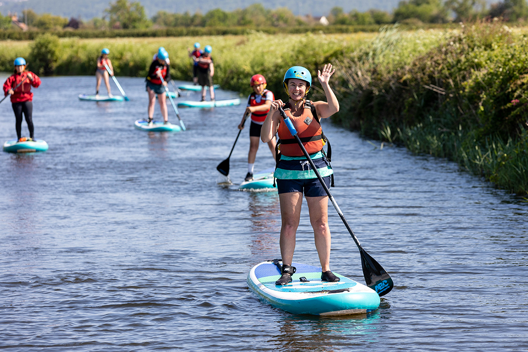 Lady on paddleboard waving 